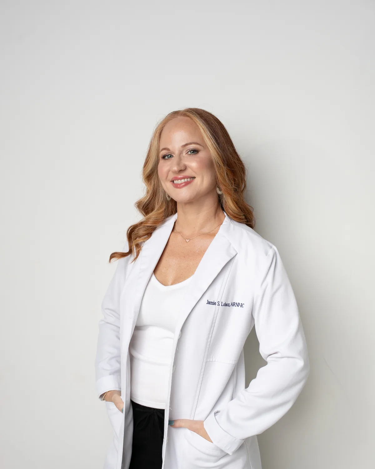 Jamie Lobacz, APRN, standing in a white coat embroidered Jamie S. Lobacz, ARNP-BC.
